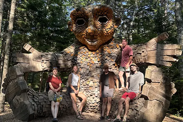 The Maine Conservation Corps team perch on one of the giant trolls at the Maine Botanical Gardens